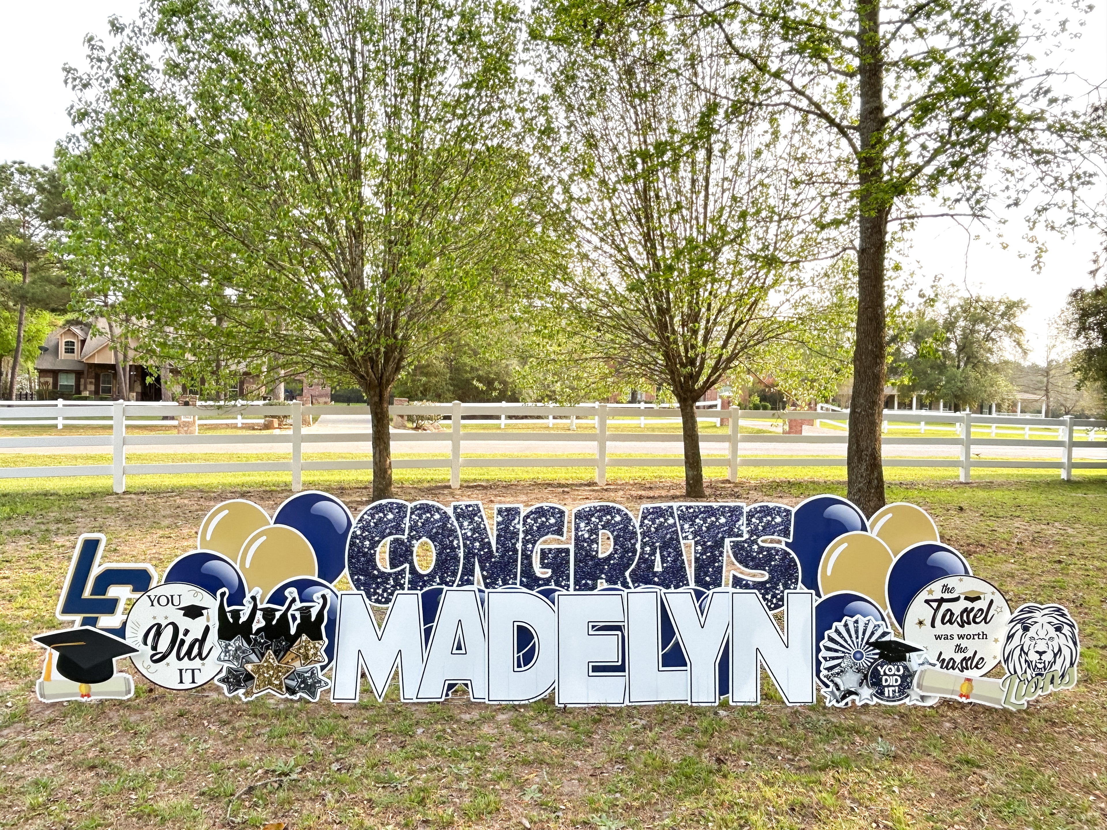 A graduation yad card rental featuring glitter graphics in navy and gold for Lake Creek High School. This custom yard sign features graduation graphics and celebration graphics in school colors. Our graduation yard cards celebrate local senior and college graduates in Montgomery, TX, The Woodlands, TX, Conroe, TX, Willis, TX, and Magnolia, TX.