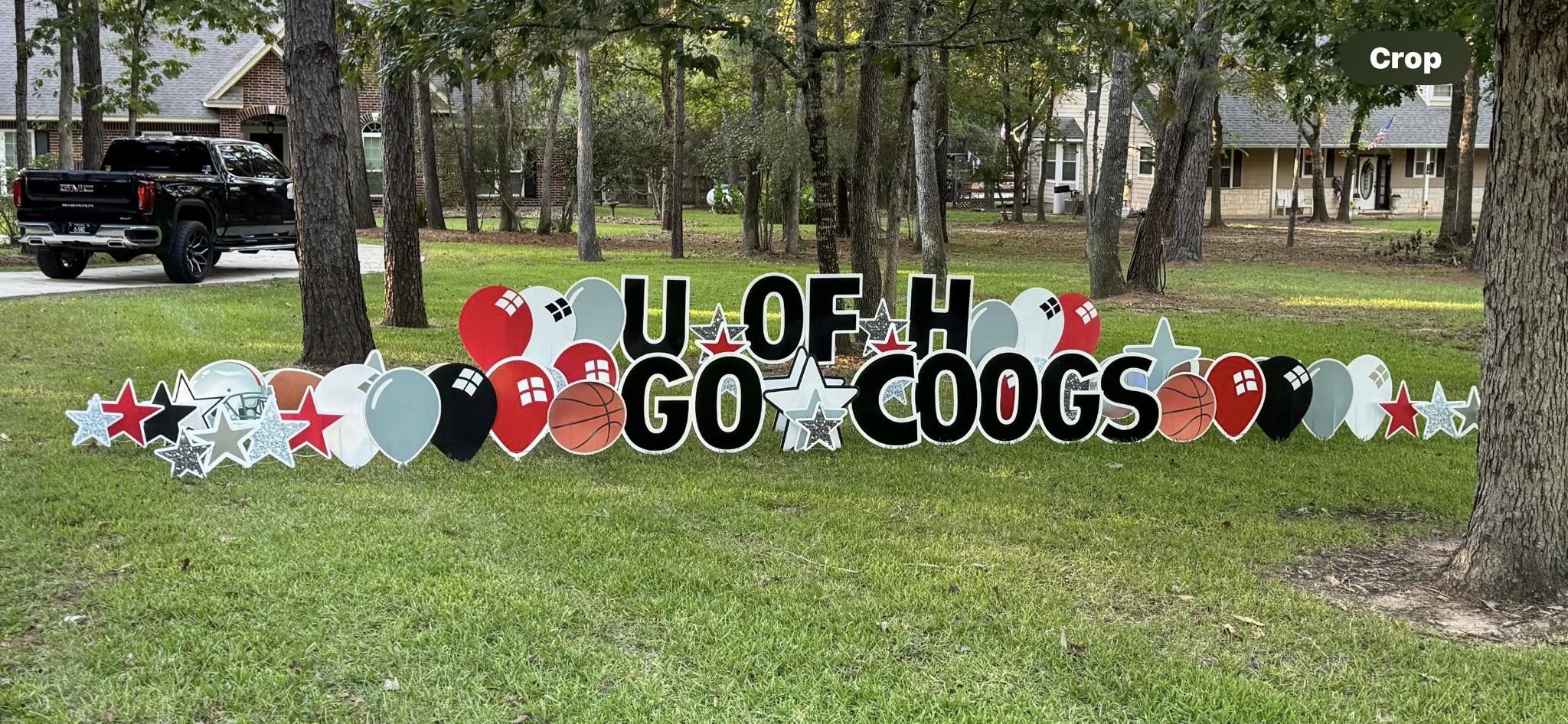 A spirited yard card display by Texas Party in the Yard, celebrating a college sports event. The setup includes a "U of H, Go Coogs!" message with the college name, sports equipment graphics, and team colors, creating a lively atmosphere in Montgomery, TX.