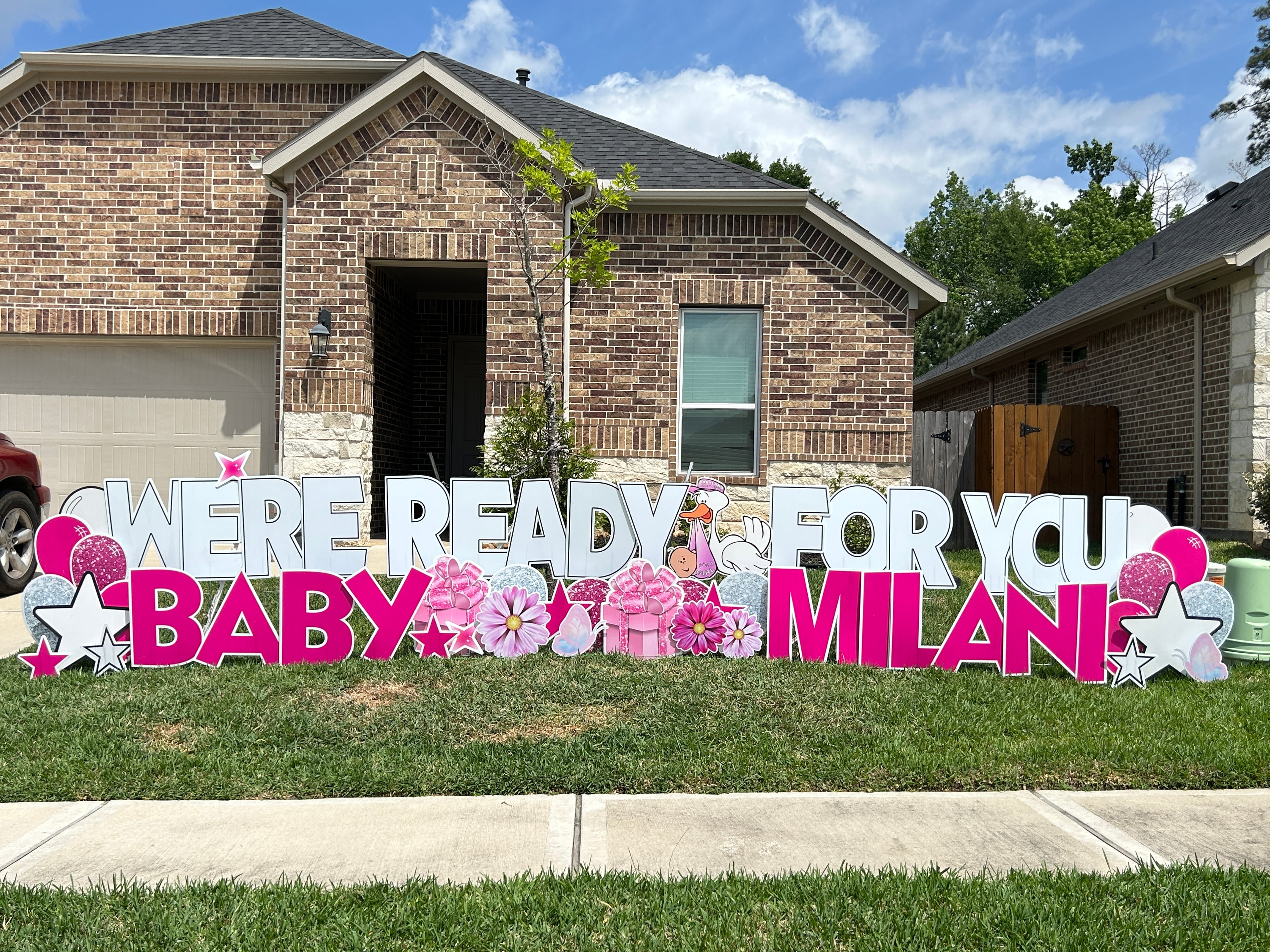 Baby shower yard card to welcome baby girl, featuring a stork, pink flowers, balloons and baby graphics in The Woodlands, Tx.
