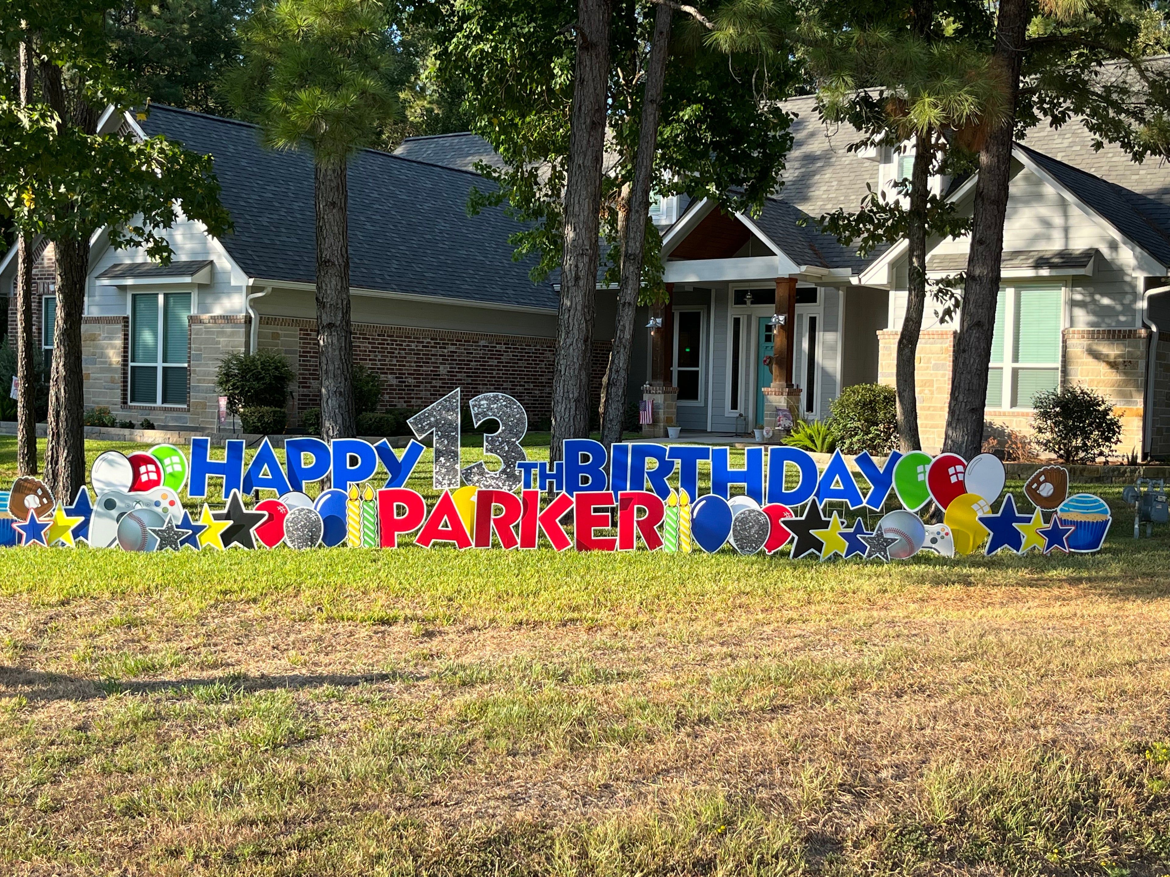 A stylish yard card display by Texas Party in the Yard, perfect for celebrating an adult's birthday. The setup includes a custom "Happy Birthday" message, the celebrant's name, elegant balloons, stars, and sophisticated graphic images, set up in a front yard in Montgomery, TX.