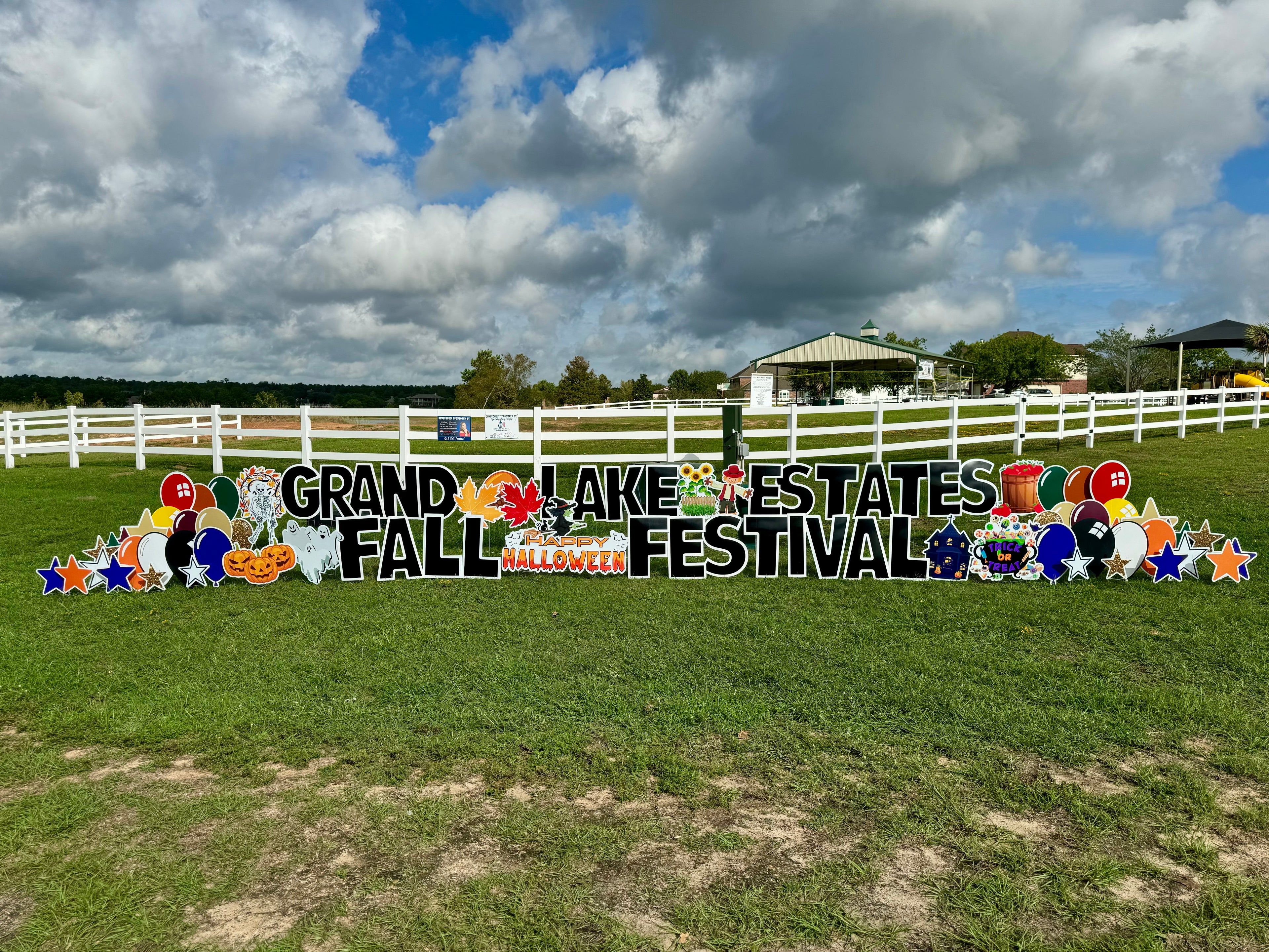  A festive yard card display by Texas Party in the Yard, celebrating a neighborhood fall festival. The setup includes a "Fall Festival" message with pumpkins, leaves, and seasonal graphics, arranged in a neighborhood common area in Montgomery, TX.